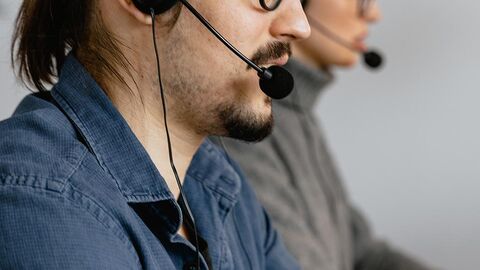 Zwei Personen tragen Headsets und arbeiten.